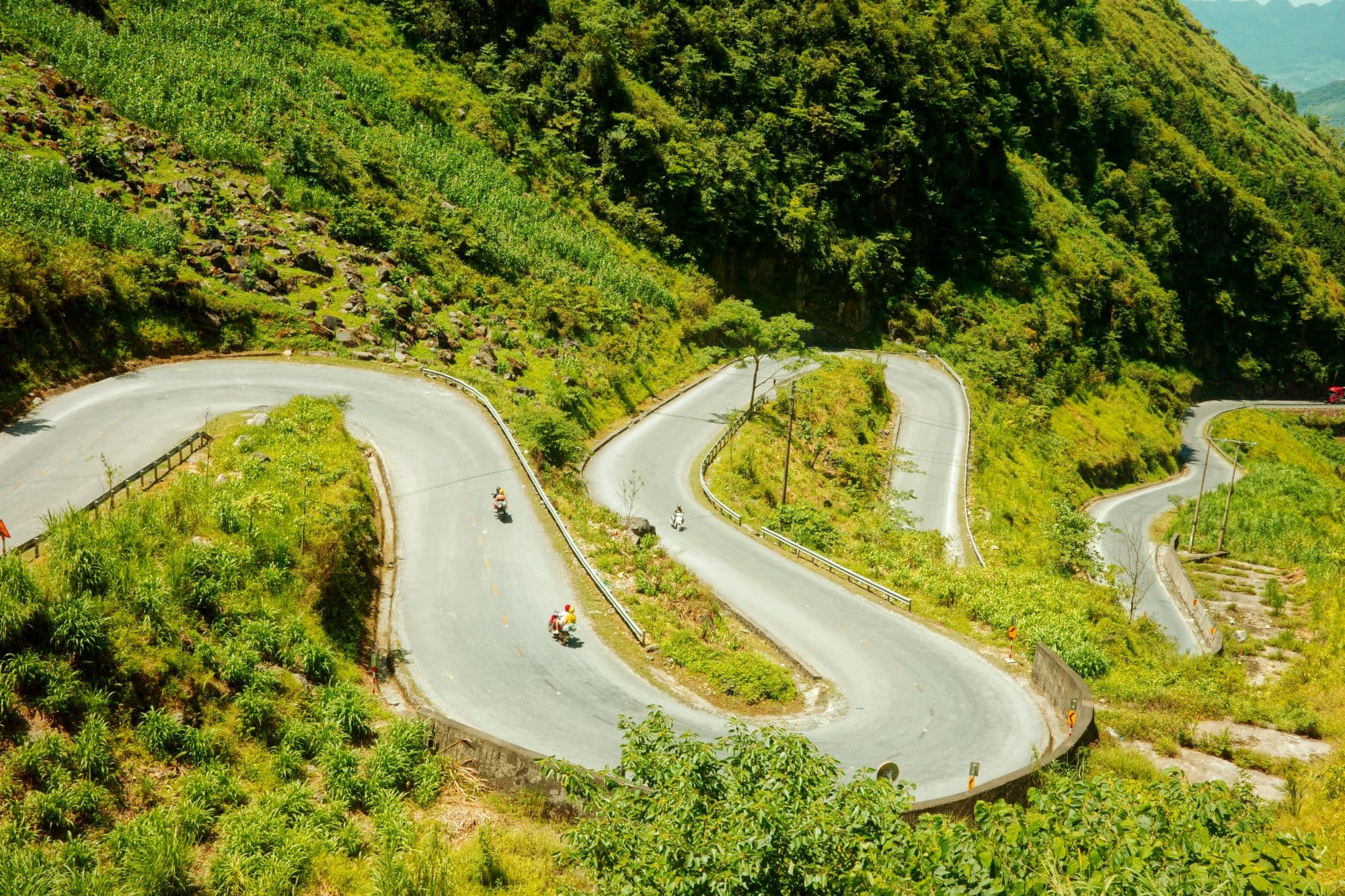 a windy mountain road with motorcyclists on it