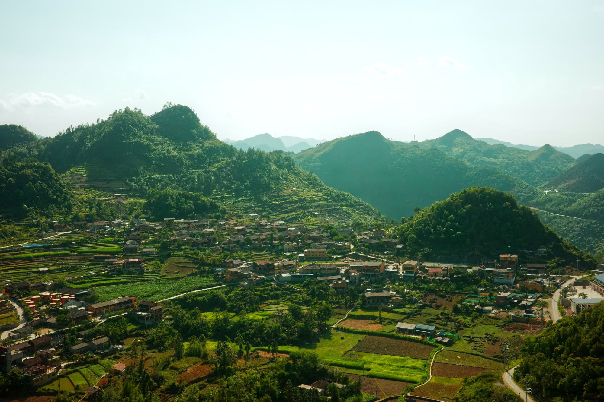 a village as seen from above, sitting between mountains with lots of greenery